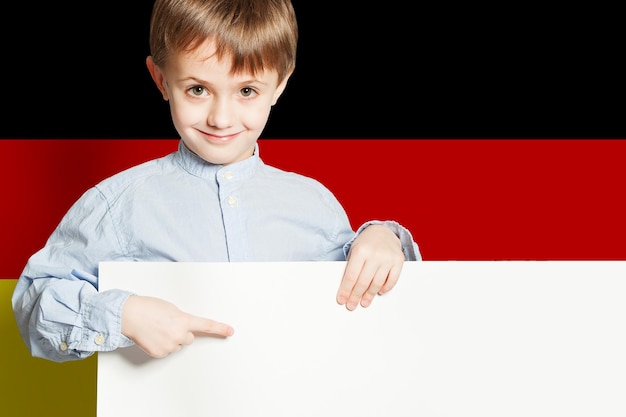 Happy child boy holding white empty banner on the Deutsch flag background