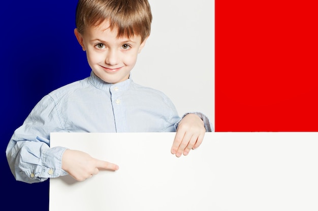 Happy child boy holding white empty banner on the Franch flag background