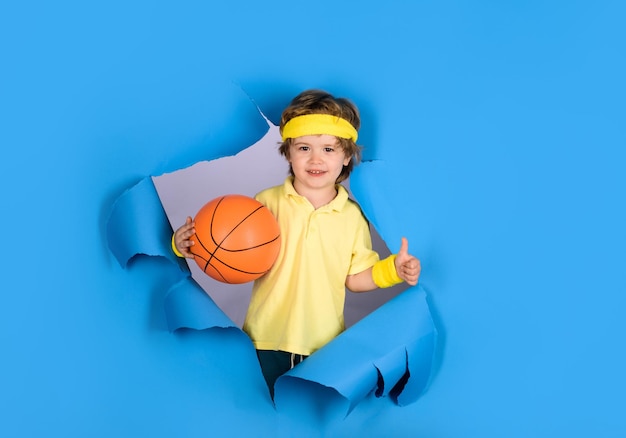 Happy child boy holds ball shows thumb up enjoy sports game kid activities little basketballer with