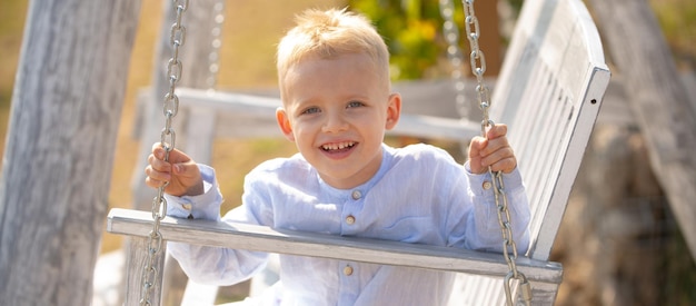 Happy child boy laughing and swinging on a swing at summer garden spring kids portrait kid emotions