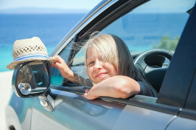 A happy child in a car by the sea in nature weekend travel