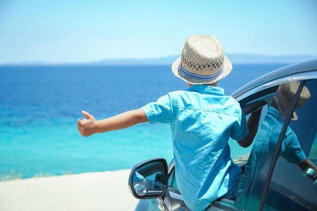 A happy child in a car by the sea in nature weekend travel