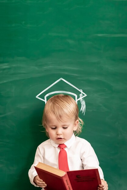 Happy child in class. Funny kid against chalkboard. Back to school. Education concept