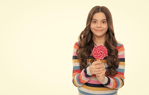 Happy child in colorful sweater with lollipop candy on stick\
isolated on white background childhood