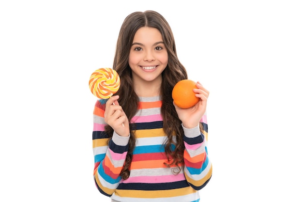 Happy child in colorful sweater with orange fruit and lollipop isolated on white healthy childhood