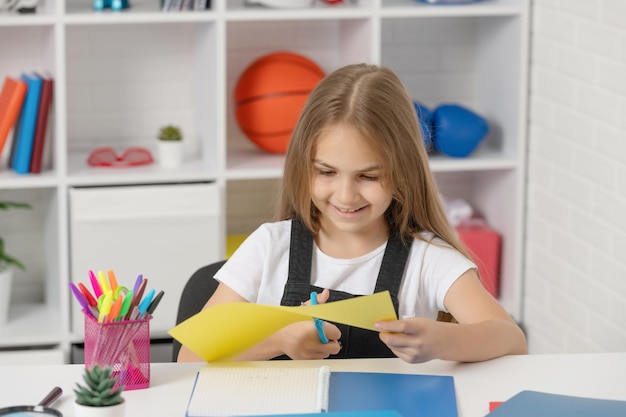 Happy child cut paper in school classroom