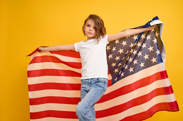 Happy child cute girl with american flag on yellow usa celebrate independence day