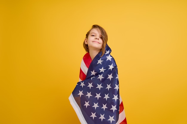 Happy child cute girl with american flag on yellow usa celebrate independence day