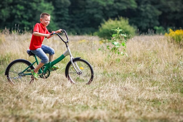 Un bambino felice in bicicletta nel concetto di parco in natura