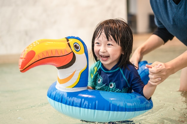 Bambino felice e papà con piscina su anello gonfiabile a forma di bucero divertendosi in una piscina