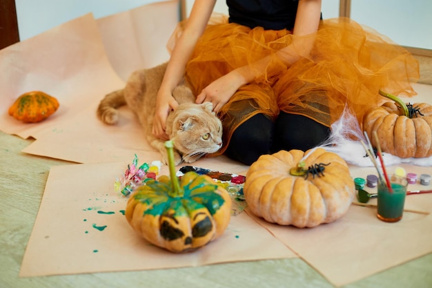 Happy child decorating a pumpkin at home with cat