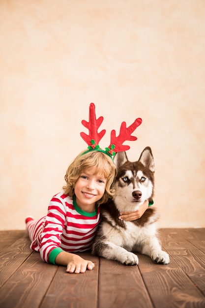 happy child and dog on christmas eve kid and pet dressed in santa claus hat