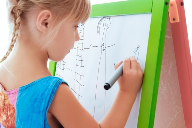 Photo happy child draws on easel on a white background