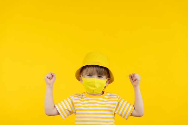 Photo happy child dreaming about vacation. portrait of kid wearing protective mask indoor