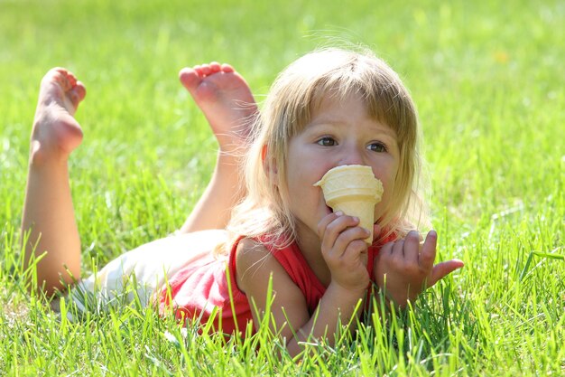 公園の自然の中でアイスクリームを食べる幸せな子供