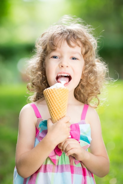 夏の公園で屋外でアイスクリームを食べる幸せな子