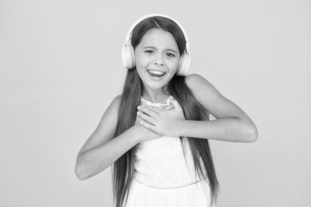 Happy child enjoy listen to music in headphones small girl\
enjoying dj music happy childhood concept back to school online\
education and communication music in wireless earphones musical\
taste