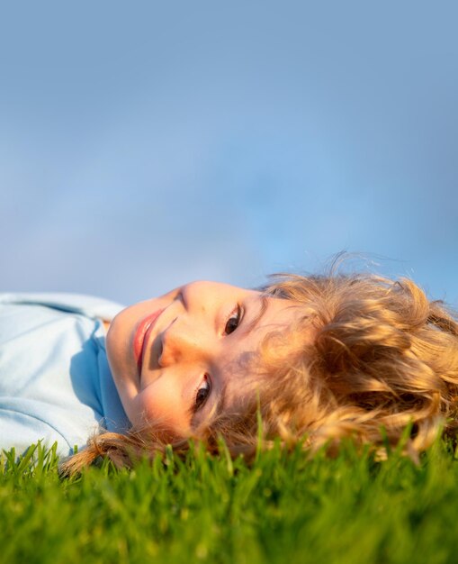 Happy child enjoying on grass field and dreaming kid relax on nature copy space on blue sky close up