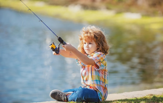 Счастливый ребенок на рыбалке Мальчик со спиннером на реке Концепция рыбалки