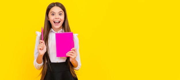 Happy child genius hold school book pointing pen up yellow background idea Banner of schoolgirl student School child pupil portrait with copy space