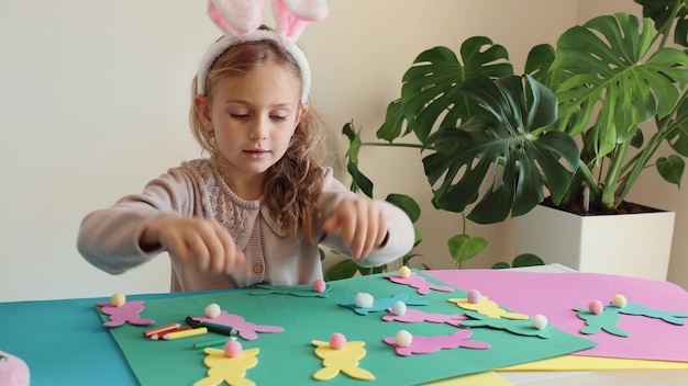Foto bambina felice con le orecchie di coniglio fa e gioca con la ghirlanda colorata di carta di pasqua coniglietto di pasqua bambini