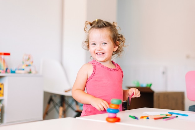 Happy child girl draws with colored pencils