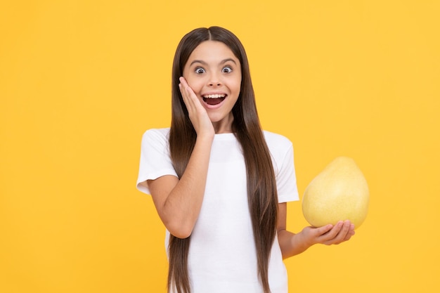 Happy child girl hold big citrus fruit of yellow pummelo or pomelo full of vitamin happiness