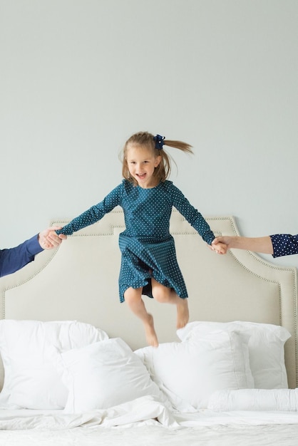 Photo happy child girl jumping on the bed and having fun