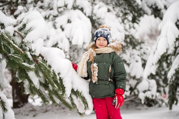 雪の降る冬の散歩で雪をかぶっている幸せな子の女の子。