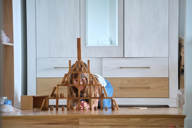 Happy child girl playing game stacking wooden toy blocks in
high pile structure. hand movement control and building
computational skills concept