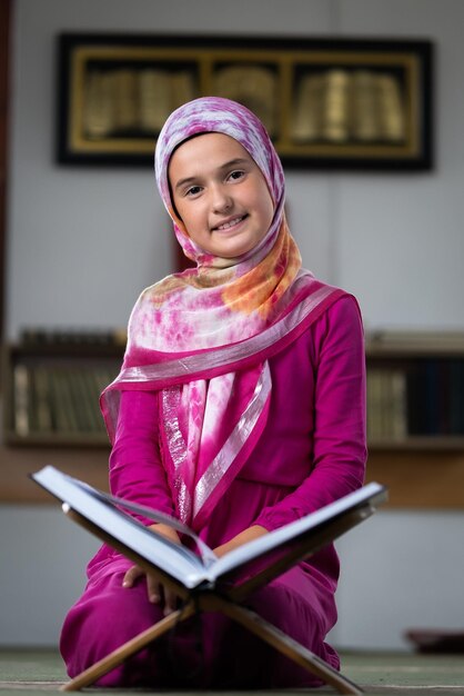 A happy child girl reading a holy book Quran inside the mosque.