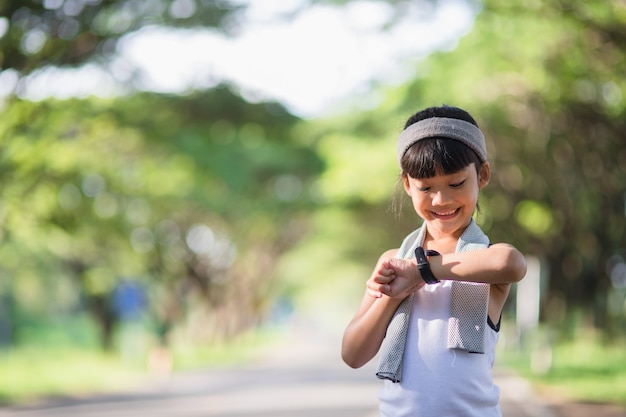 自然の中で夏に公園で走っている幸せな子の女の子。暖かい日光のフレア。