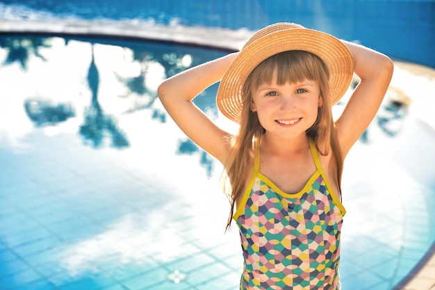 Happy child girl smiling blue water of swimming pool summer vacation concept