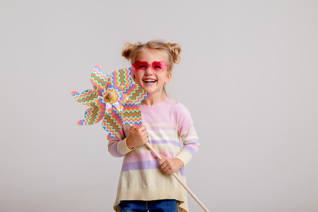 Happy child girl in sunglasses holding a baby windmill