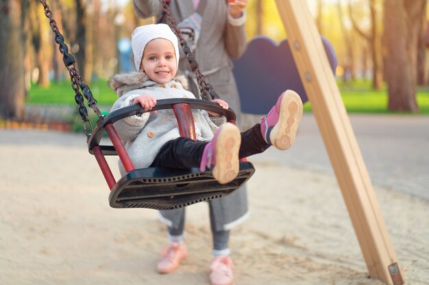 Happy child girl on swing in sunset fall