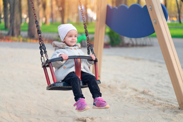 Happy child girl on swing in sunset fall