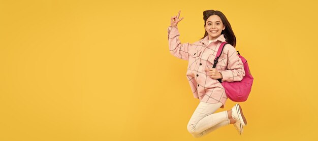 Happy child girl wear pink checkered shirt jumping school backpack full of energy Banner of school girl student Schoolgirl pupil portrait with copy space