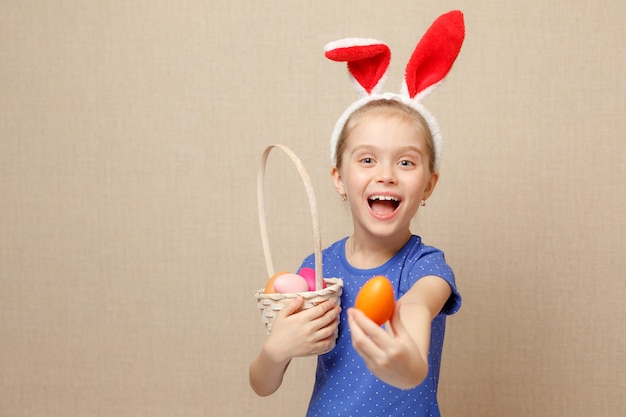 Ragazza felice del bambino con le orecchie del coniglietto e delle uova di pasqua