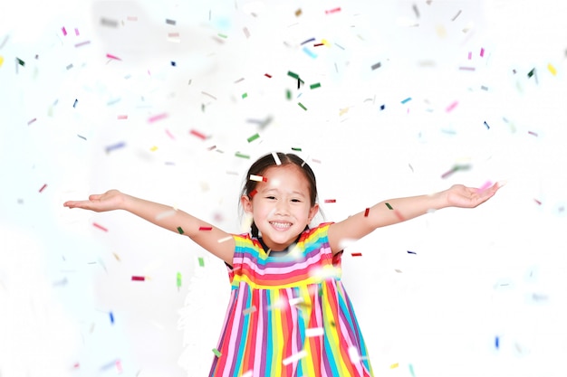 Ragazza felice del bambino con i coriandoli su fondo bianco. felice anno nuovo o concetto di congratulazione.