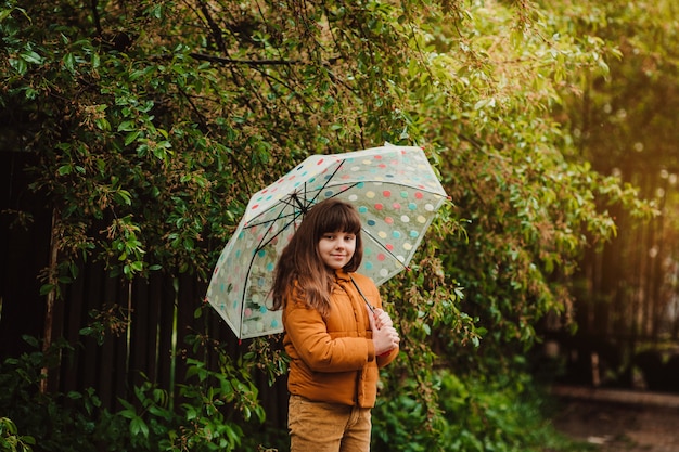 Happy child girl with an umbrella on a walk