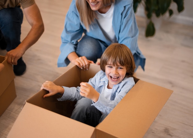 Foto bambino felice che si diverte con le scatole nella sua nuova casa