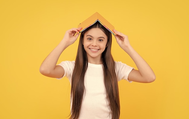 Happy child hold book on yellow background school