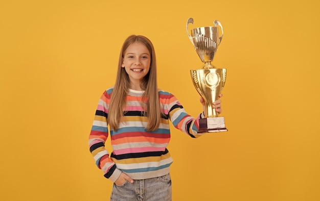 Happy child hold golden cup achievement award celebrating\
school success