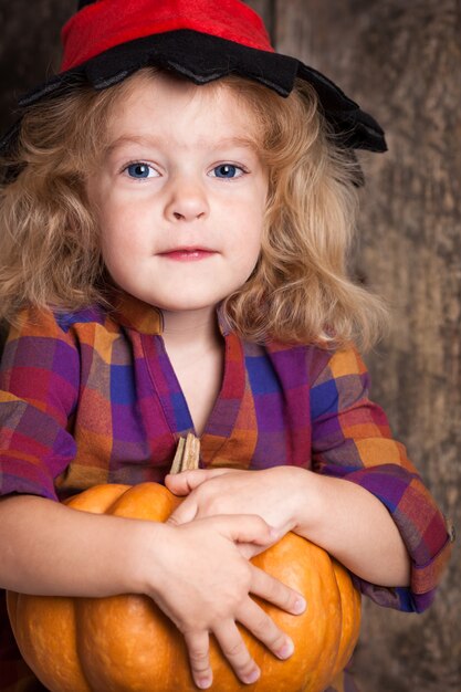 Happy child holding big pumpkin. Halloween concept