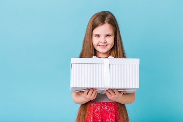 Happy child holding birthday presents on a blue wall