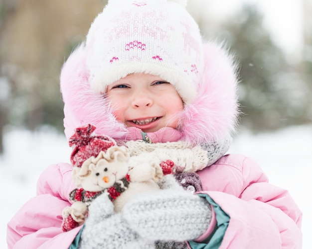 Photo happy child holding christmas decoration in winter park. outdoors shot