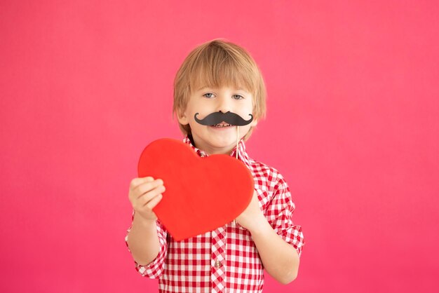 Happy child holding heart shaped blackboard blank