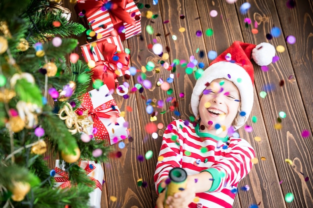 Happy child holding party popper. Funny kid on Christmas eve. Xmas holiday concept