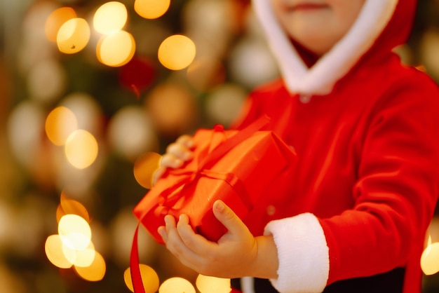 Happy child holding red gift box on the background lights