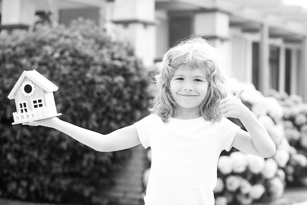 Foto bambino felice che tiene la casa del giocattolo nelle mani contro il nuovo concetto di casa di alloggi per bambini